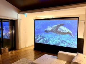 a large screen tv in a living room with a turtle on it at Rayful Hayama in Hayama