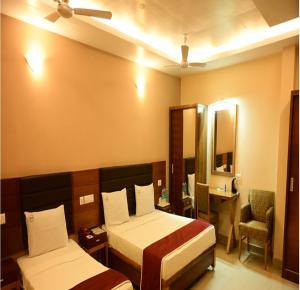 a hotel room with two beds and a mirror at Hotel PAMS in Mayiladuthurai