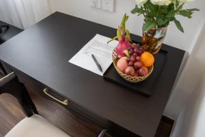 a bowl of fruit on a table with a vase at Can Gio Park Hotel in Cần Giờ