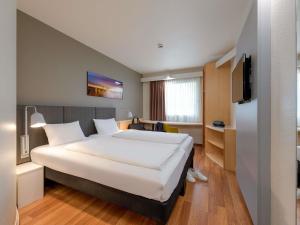 a hotel room with a large bed and a tv at ibis Hotel Köln Airport in Cologne