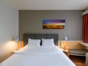 a bedroom with a large white bed and a desk at ibis Hotel Köln Airport in Cologne