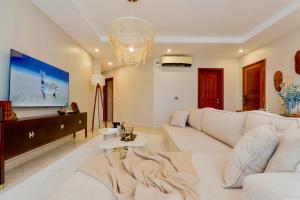 a living room with a white couch and a chandelier at Naia Residence - 2BR Oceanview in Dar es Salaam