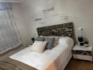 a bedroom with a bed with white sheets and a sign on the wall at A&M Burela Costa in Burela de Cabo