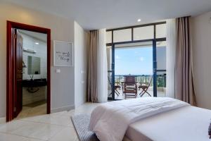 a bedroom with a bed and a view of a balcony at Naia Residence - 2BR Oceanview in Dar es Salaam +19 photos