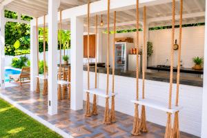 a porch with four white chairs and a kitchen at Kelapa Lodge - Lombok - in Senggigi