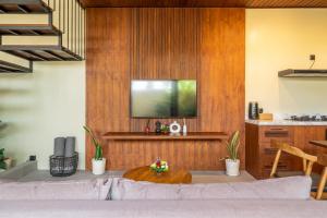 a living room with a tv on a wooden wall at Nala Villa - Peaceful Hideaway with Pool & Yoga Space in Canggu