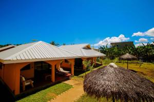 a building with a straw roof next to a house at Résidence Swiss Nosy be in Nosy Be