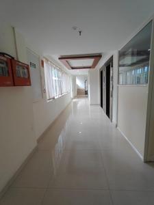 an empty hallway of a building with white floors and windows at Tyche Stays in Trivandrum