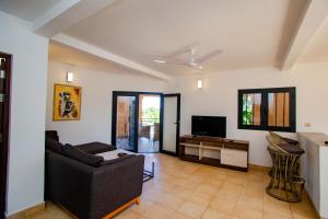 a living room with a couch and a tv at Résidence Swiss Nosy be in Nosy Be