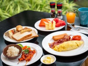 a table with plates of breakfast food on it at Grand Mercure Bangkok Asoke Residence in Bangkok