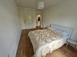 a bedroom with a white bed and a wooden floor at Spacious Bright Modern Apt With Garden in Dublin
