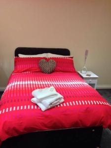 a red bed with two towels and a heart pillow at Airport Tavern Accommodation in Felton