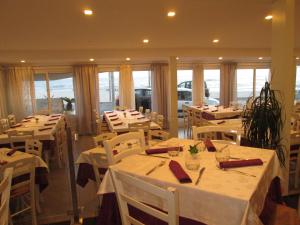 a restaurant with white tables and white chairs and windows at B&B Elisir in Gela