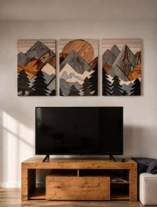 a television in a living room with four paintings on the wall at mansarda roulette in Saint Vincent