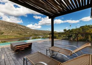 a deck with chairs and a bench and a river at Casa do Teuler - Lapinha da Serra in Santana do Riacho