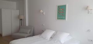 a white bedroom with a bed and a chair at Les Cabines in Houlgate