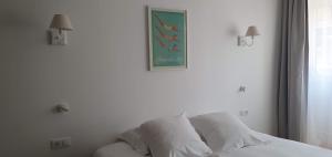 a bed with white sheets and a picture on the wall at Les Cabines in Houlgate