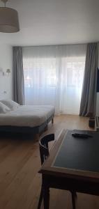 a bedroom with a bed and a table and window at Les Cabines in Houlgate