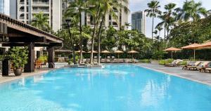 a large swimming pool with chairs and umbrellas at The Peninsula Manila in Manila
