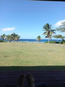 a person laying on a porch looking at the beach at Kuki Beach Bach in Rarotonga +4 photos