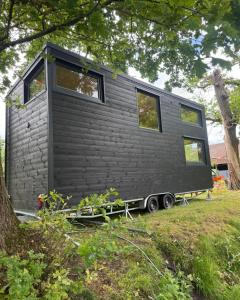 a black tiny house on a trailer in a yard at Tiny House Porto op Domein Kiewit in Hasselt