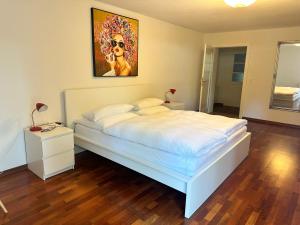 a bedroom with a white bed with a painting on the wall at Memminger Stadtnest Donaustr 4 in Memmingen +6 photos