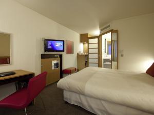a hotel room with a bed and a desk and a television at Novotel Liverpool Centre in Liverpool