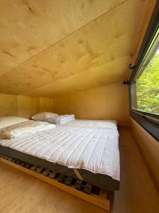 a bed in a small room with a window at Tiny House Porto op Domein Kiewit in Hasselt