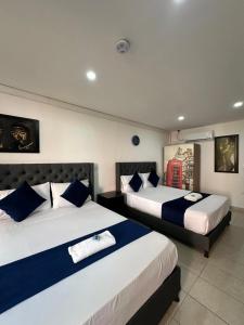 a bedroom with two beds with blue and white pillows at Hotel Lleras # 1 in Medellín