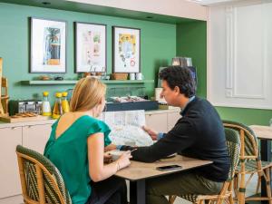a man and woman sitting at a table looking at a map at Aparthotel Adagio Paris Haussmann Champs Elysées in Paris