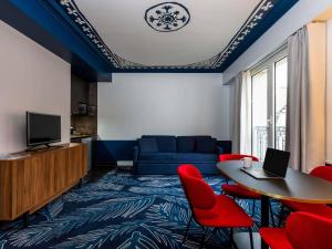 a living room with a couch and a table and red chairs at Aparthotel Adagio Paris Haussmann Champs Elysées in Paris
