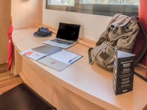 a desk with a laptop and a bag on it at Ibis Girona in Girona