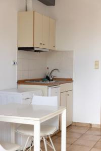 a kitchen with a white table and white cabinets at Elia mini suite 2 in Larisa
