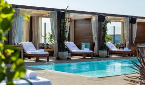 a pool with chaise lounge chairs and a table at Dream Hollywood, by Hyatt in Los Angeles