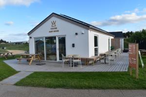 a white building with tables and chairs in front of it at Viking Surf & Stay in Klitmøller