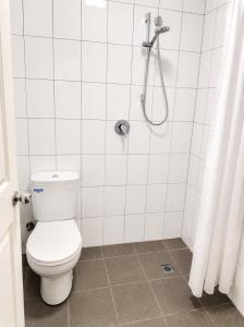 a white bathroom with a toilet and a shower at Coastal Studio in Seacliff