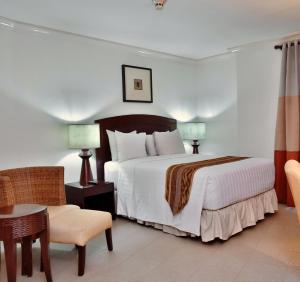 a hotel room with a bed and a chair at Crown Regency Suites Mactan in Mactan +33 photos