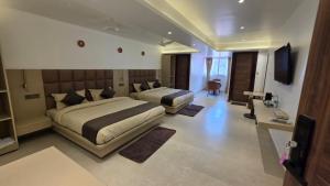 a large bedroom with two beds and a television at Hotel Anukampa in Rāmgarh