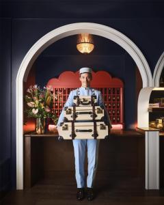 a chef holding a tray of food in a kitchen at The Georgian, in The Unbound Collection by Hyatt in Santa Monica