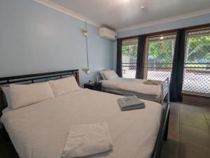 a bedroom with two beds and two windows at Hervey Bay Flashpackers in Hervey Bay +53 photos