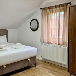 ein Schlafzimmer mit einem Bett und einem Fenster mit einem Spiegel in der Unterkunft Ponti's Villa in Buşteni