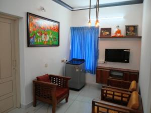 a living room with a tv and a couch and chairs at Kasi Heritage Home Near Sree Padmanabha Swami Temple 800m in Trivandrum