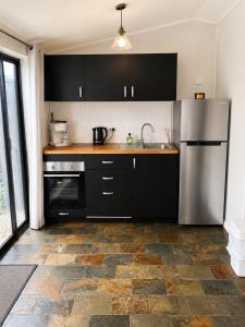 a kitchen with black cabinets and a stainless steel refrigerator at Coastal Studio in Seacliff +2 photos