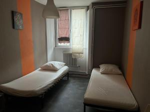 two beds in a small room with a window at Le Kompost'l chambre en gîte 2 pers in Saint-Privat-dʼAllier