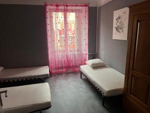 a room with two beds and a window with pink curtains at Le Kompost'l chambre en gîte 2 pers in Saint-Privat-dʼAllier