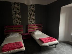 two beds in a black room with red sheets at Le Kompost'l chambre en gîte 2 pers in Saint-Privat-dʼAllier