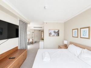 a bedroom with a white bed and a flat screen tv at Serain Residences on Legends in Gold Coast