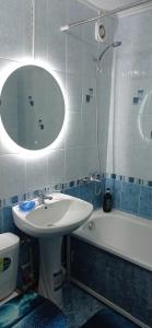 a bathroom with a sink and a tub and a mirror at Уютная 1 комнатная квартира на Сейфуллина 21 in Balqash