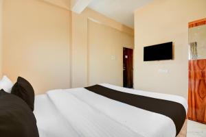 a bedroom with a bed and a tv on the wall at Super Hotel O Dehu Pune Formerly Gathaa Inn in Dehu +26 photos