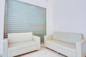 two white chairs and a couch in a room at Super Hotel O Dehu Pune Formerly Gathaa Inn in Dehu